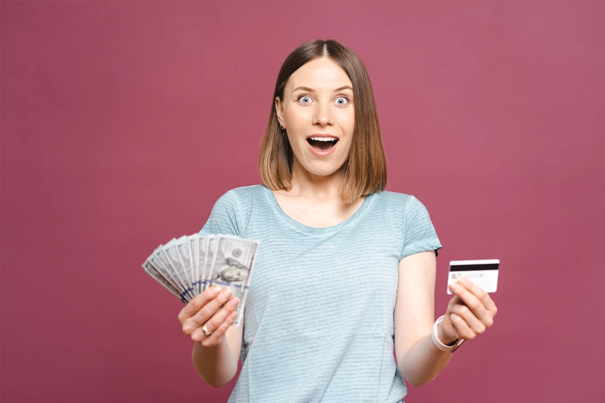 Surprised woman holding cash and credit card.