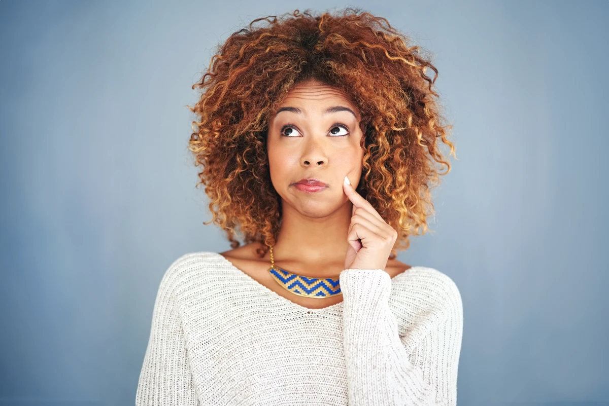 Woman thinking with finger on cheek.