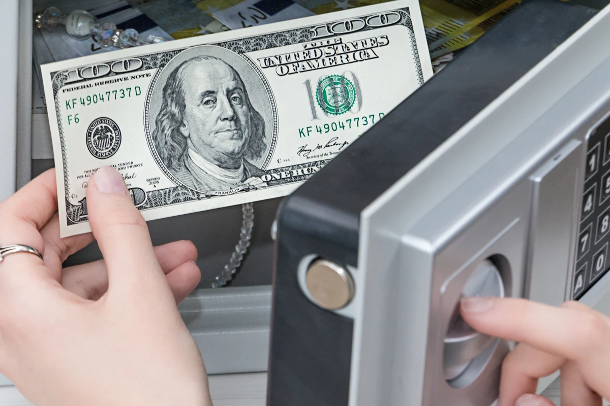 Person depositing $100 bill into a safe
