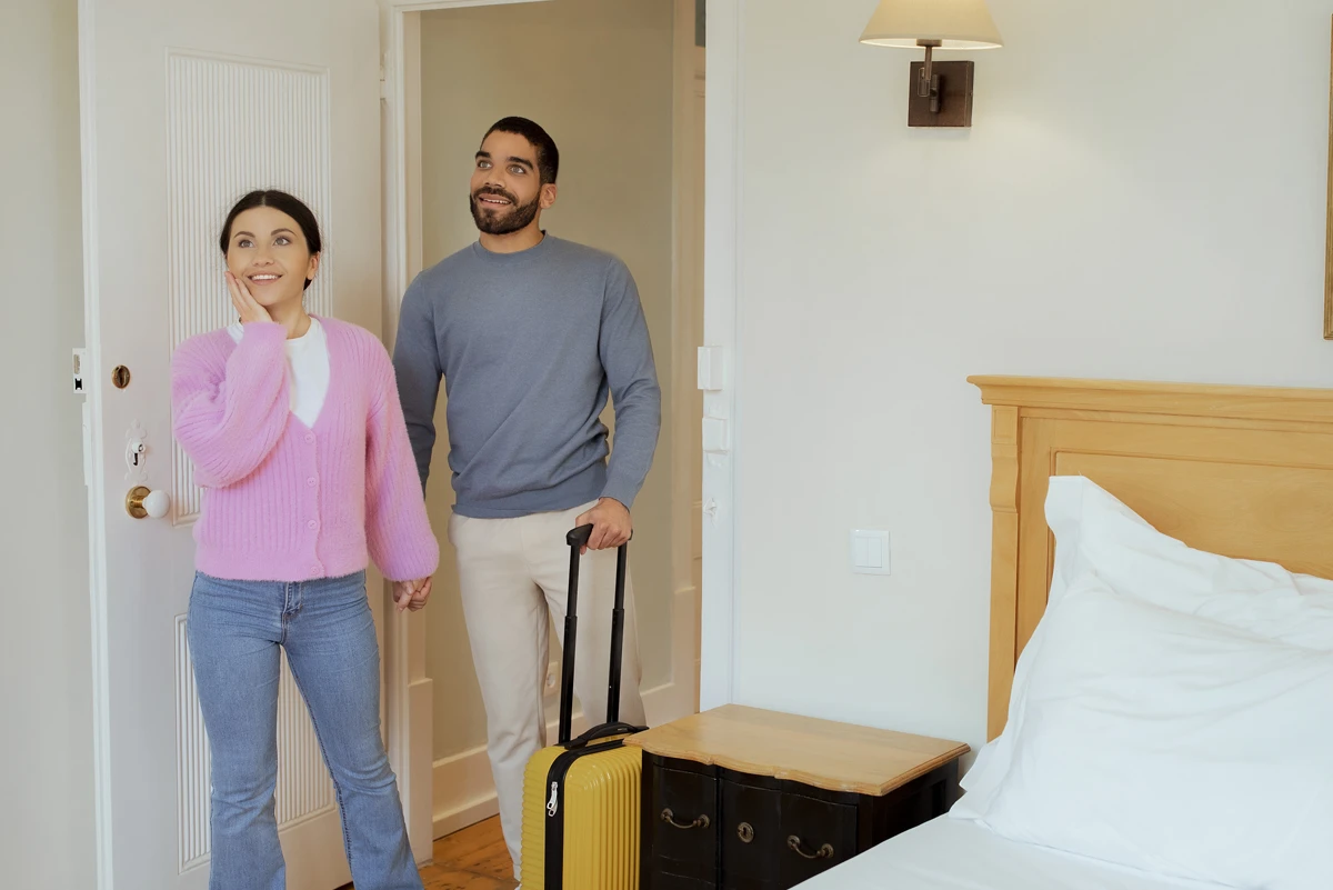 Couple entering cozy hotel room with luggage.