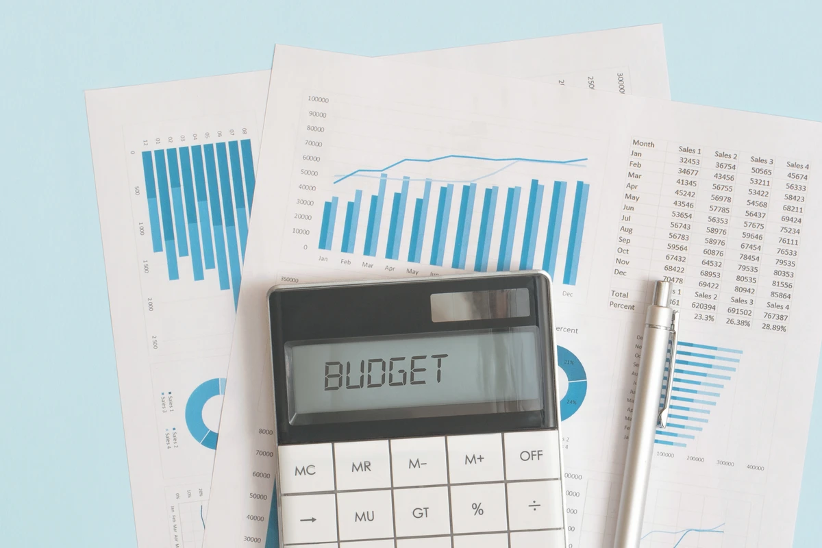 Calculator sitting on top of budget documents and charts, representing intentional planning and disciplined spending.