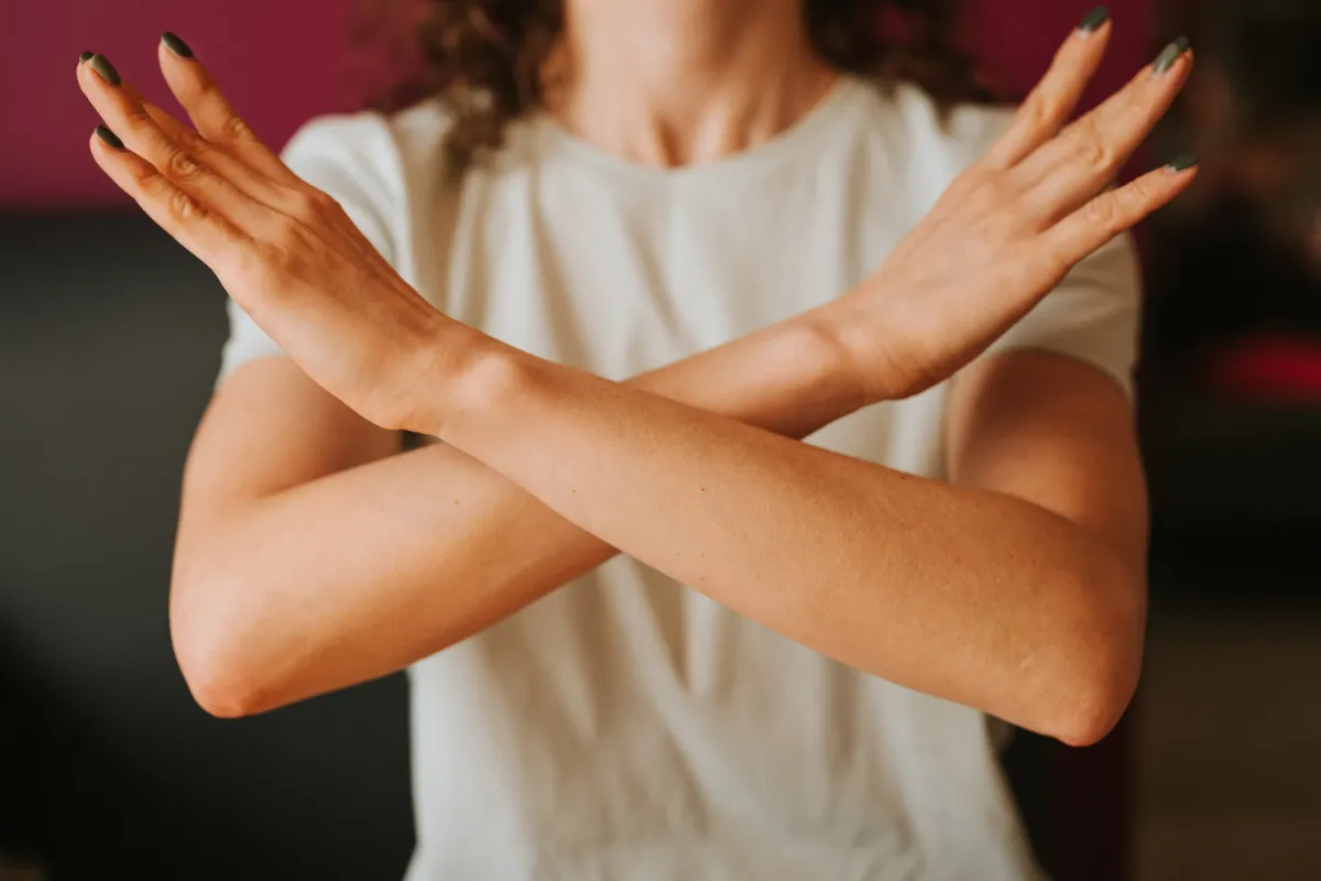 Person crossing their arms in front of their chest, symbolizing refusal or disapproval.
