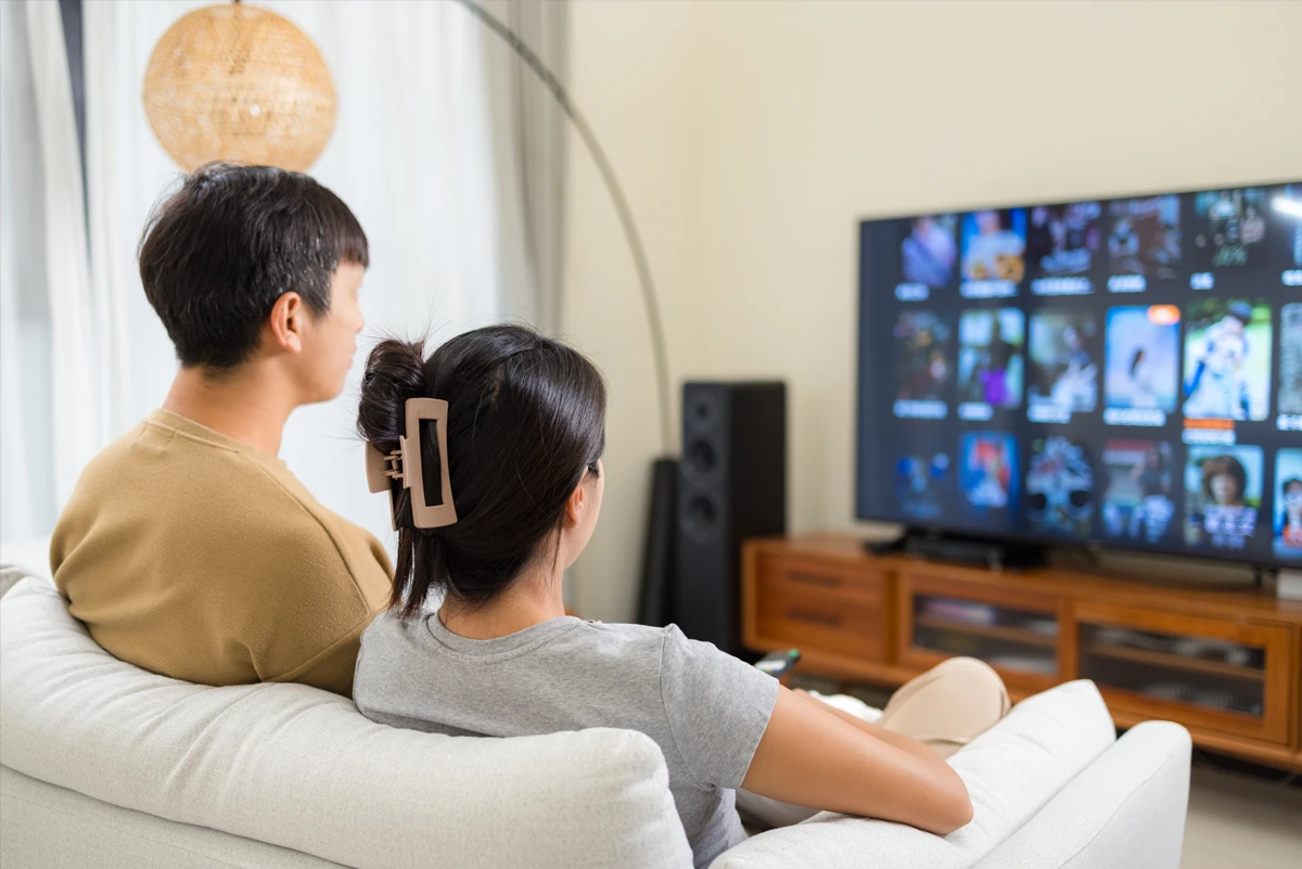 Couple watching TV with streaming options displayed.