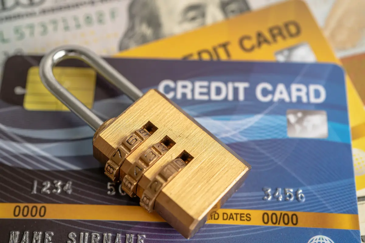 A combination lock placed on top of two credit cards, with banknotes partially visible underneath.