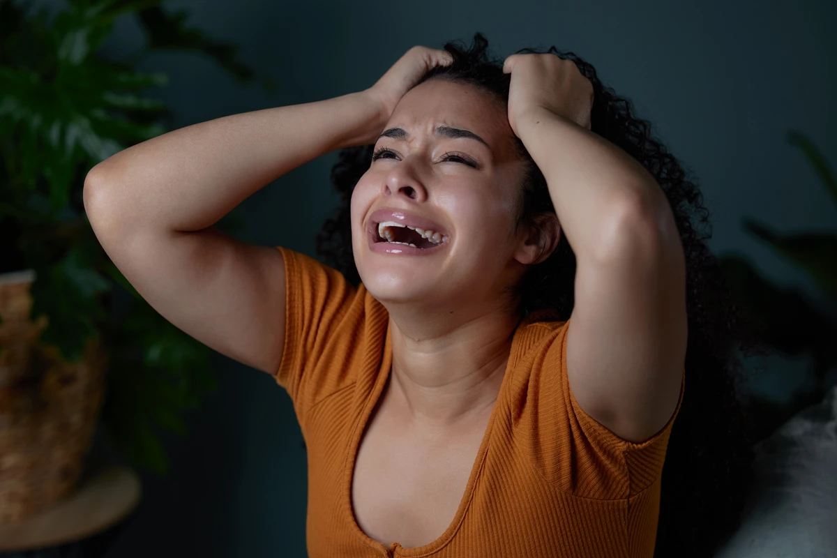 a woman holding her head and crying