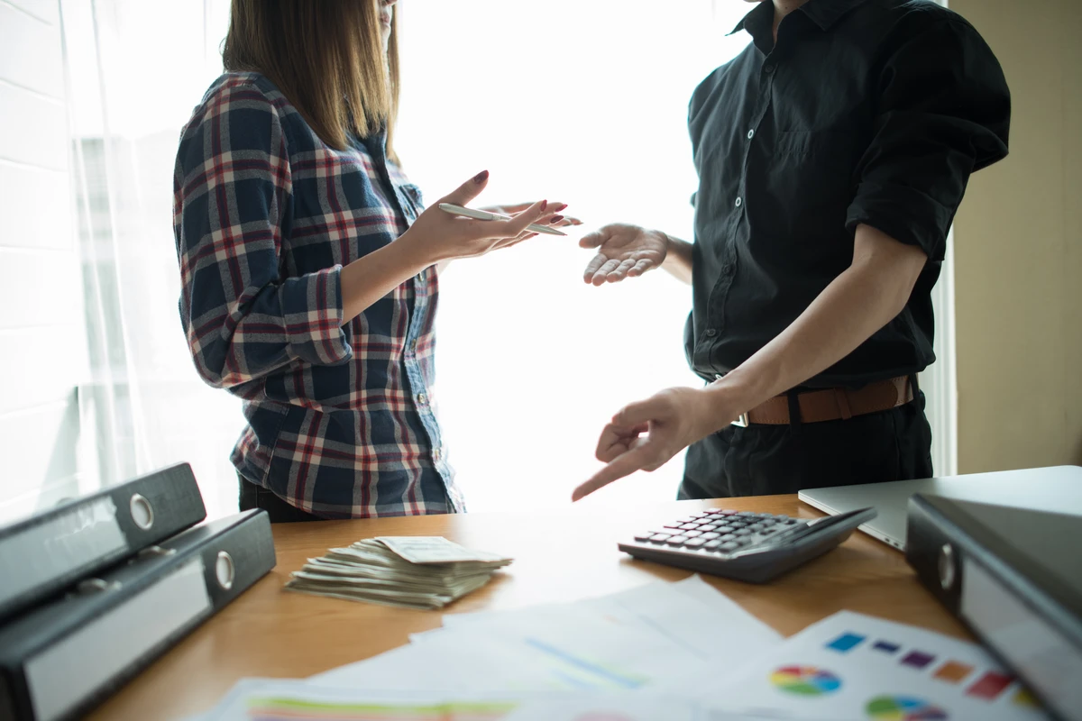 A couple reviews documents and a calculator while estimating how long-term care costs could affect their household plan