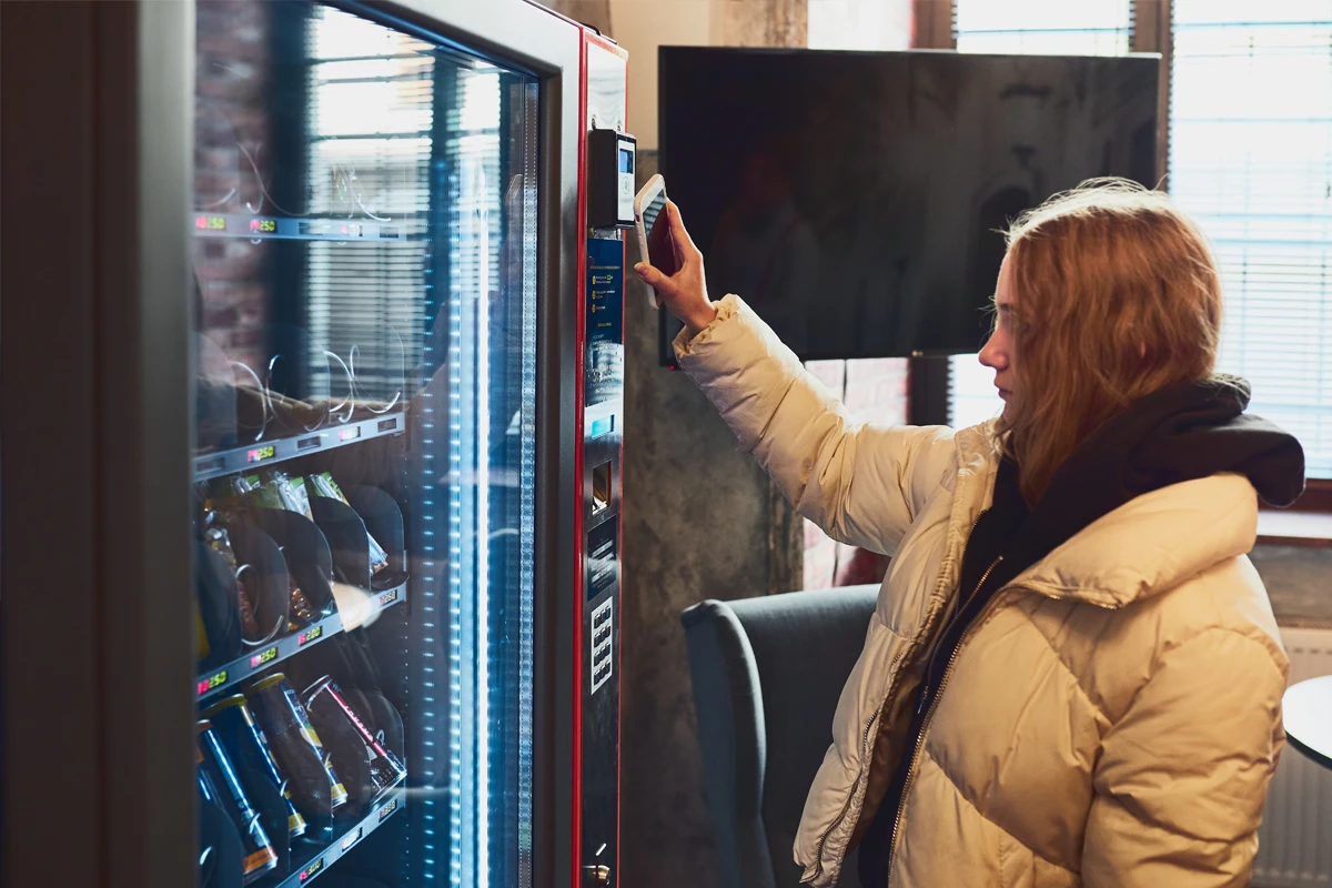Woman selecting snack from vending machine indoors
