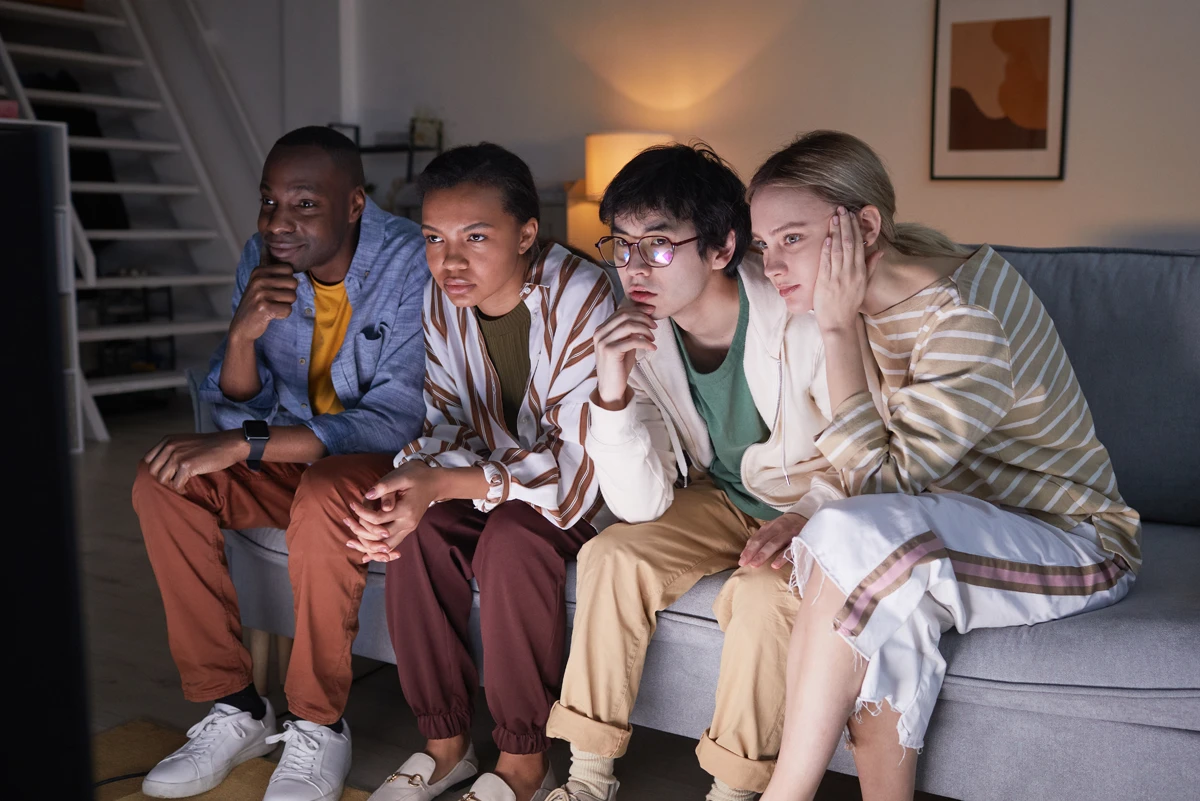 Four people watching TV intently on couch.