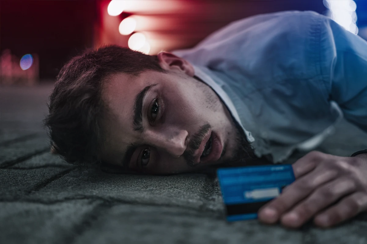 Man lying on ground with credit card, blurred lights