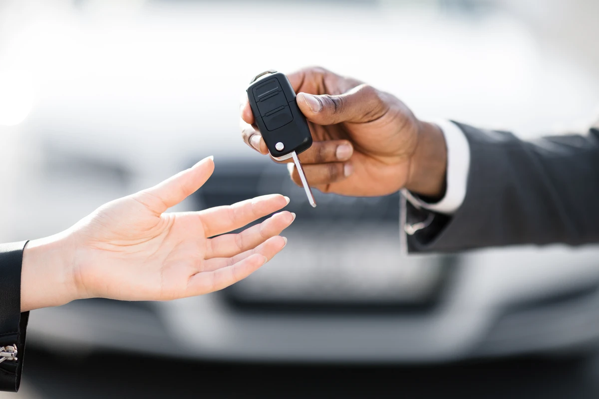 Person handing over car keys to another person