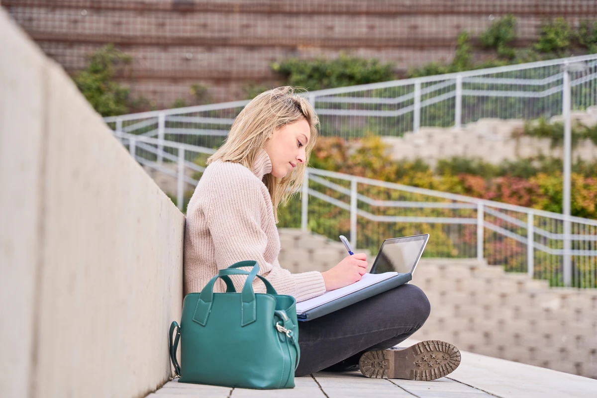 Person writing in a notebook, representing a regular financial goal review and adjustment habit.