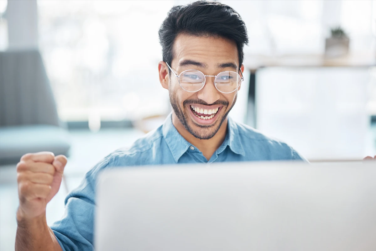Man celebrating success at computer, smiling broadly.