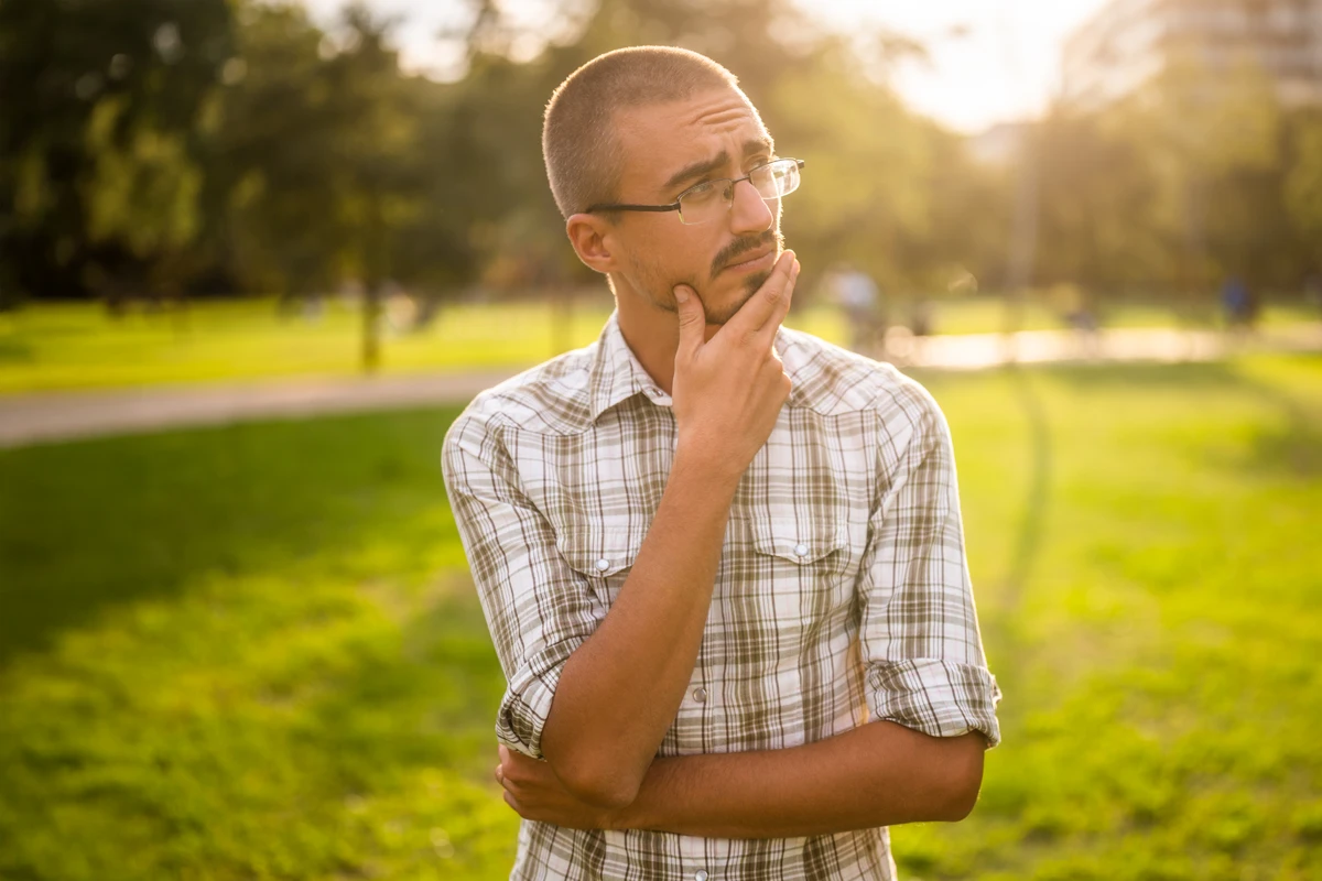 Pensive man in park during sunset