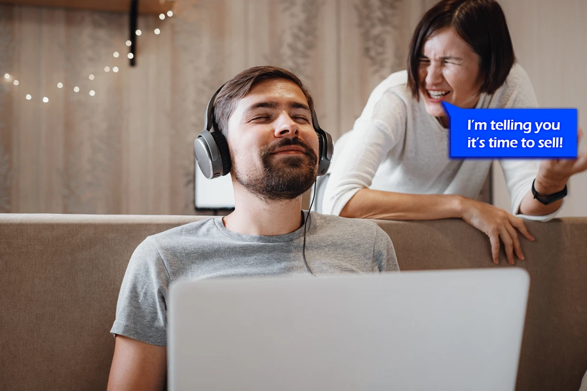 Man with headphones ignoring excited woman at laptop