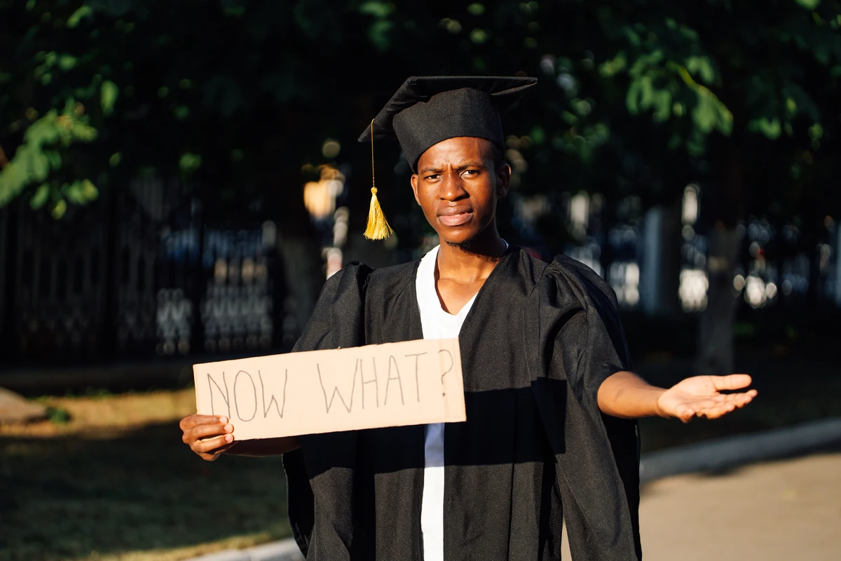 a man in a graduation gown holding a sign