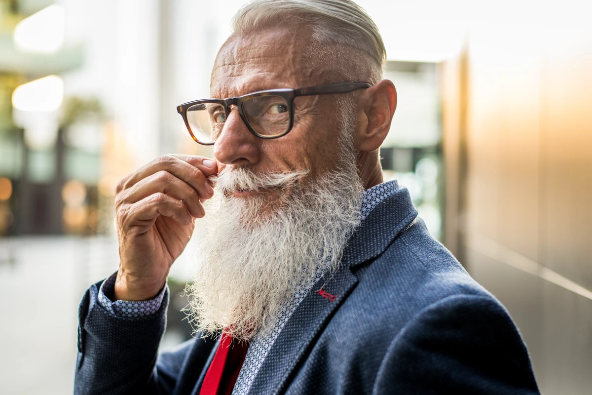 Elderly man with glasses and white beard.