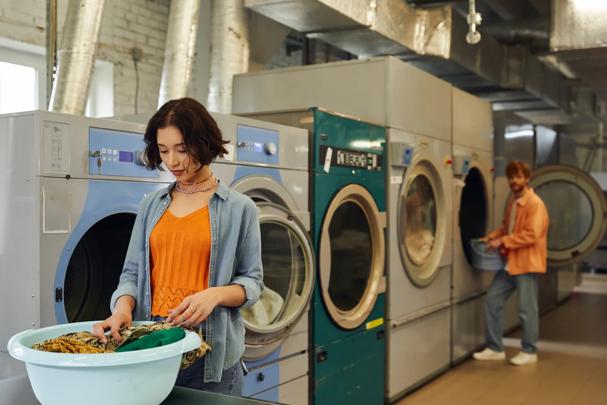 Young adults using washing machines in a laundromat