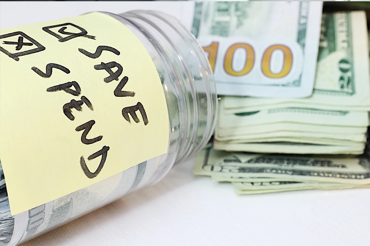 Note labeled 'Save, Spend' on jar with US dollars