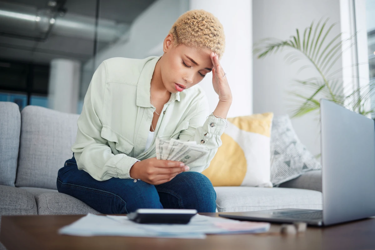 Worried woman managing finances with laptop at home