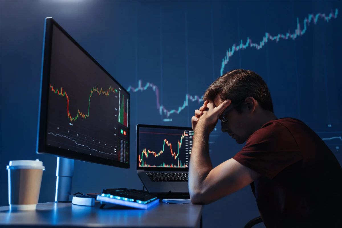 A stressed investor looking at falling market charts, illustrating how loss aversion can trigger rushed selling.