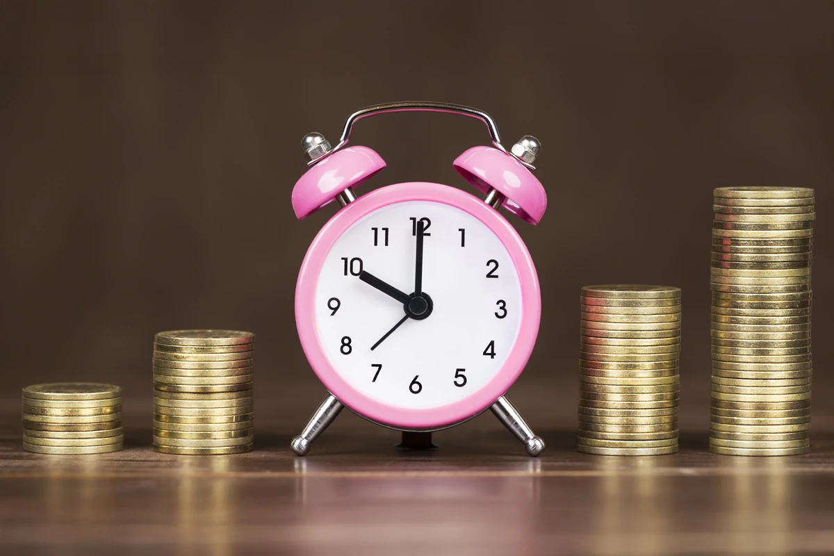 Pink alarm clock and increasing money stacks
