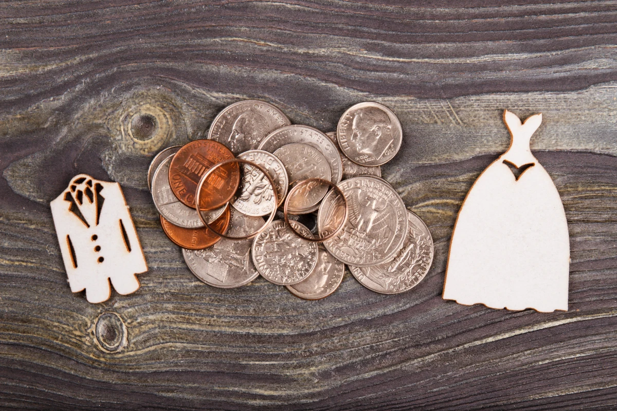 Wedding icons and coins on wooden background
