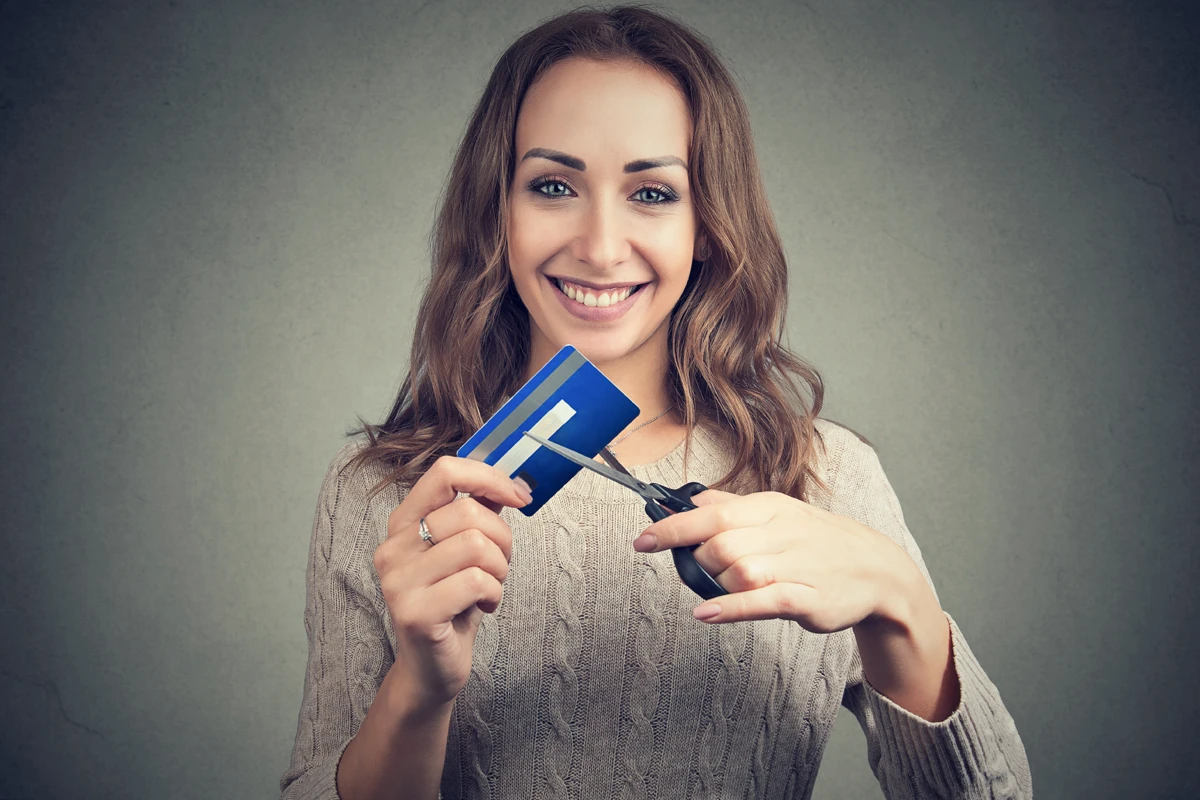 Smiling woman cutting credit card