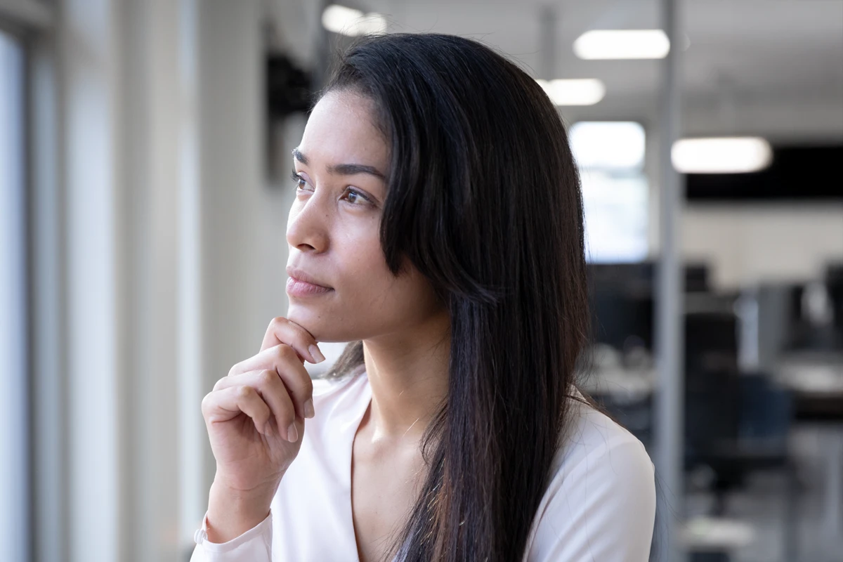 Thoughtful woman looking out office window