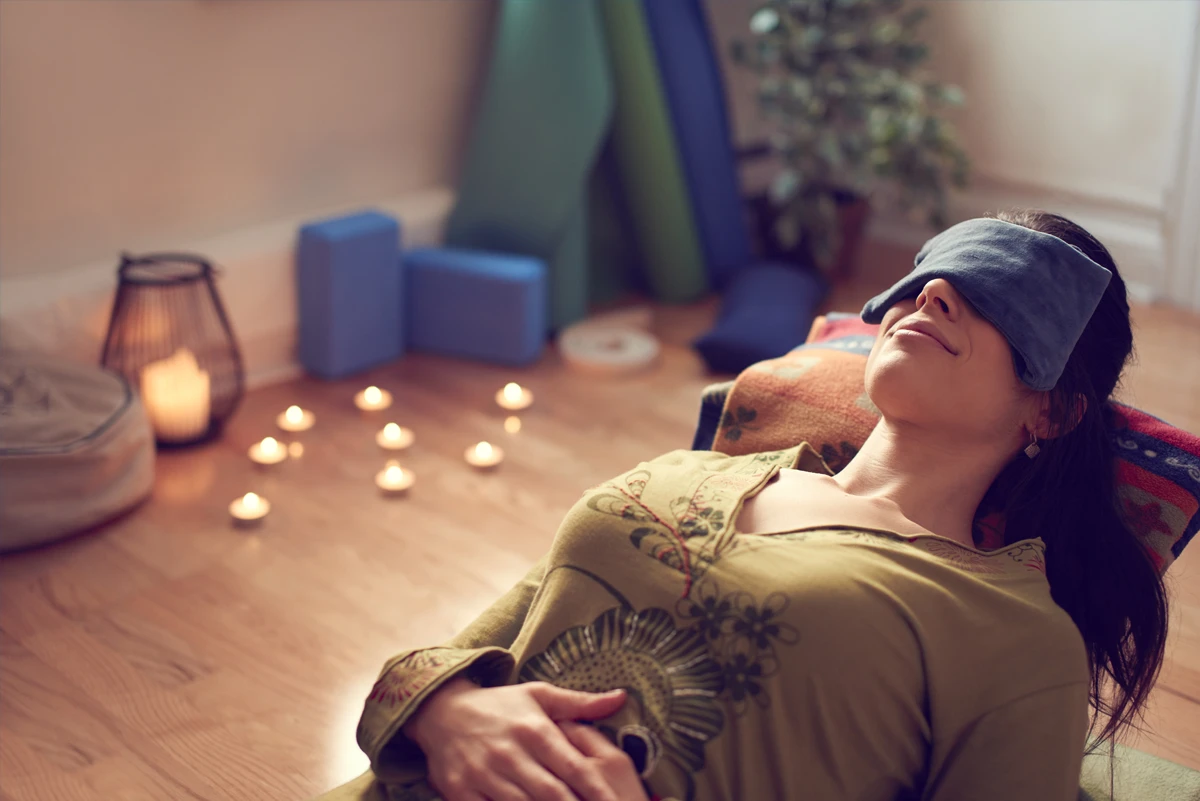 Woman relaxing in candlelit yoga studio.