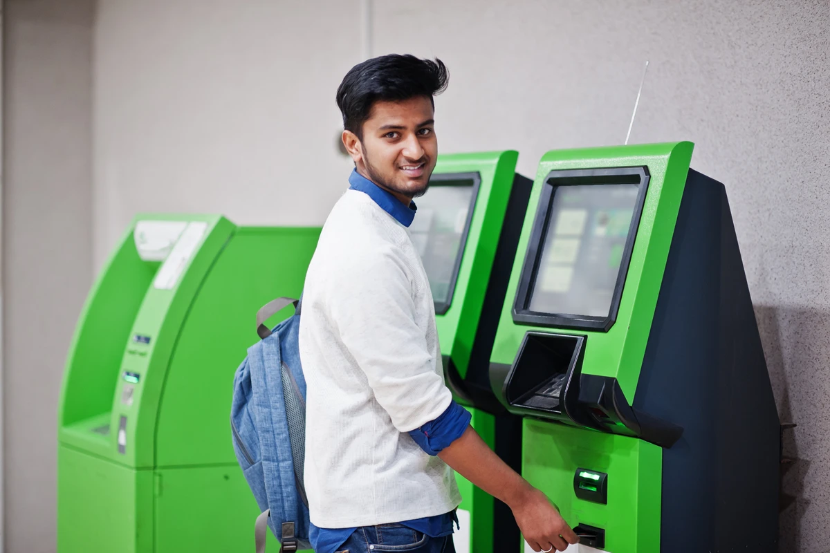 Young man using ATM machine indoors