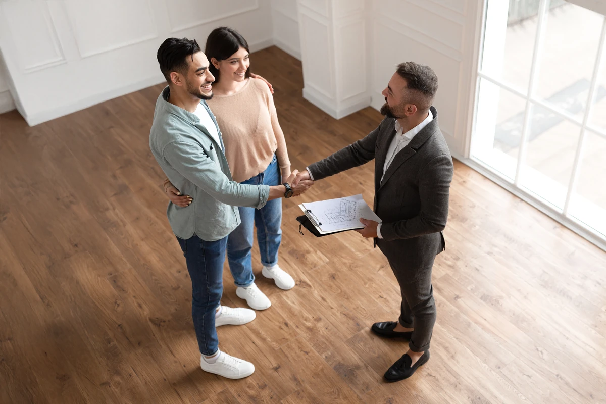 Realtor shaking hands with couple in new home