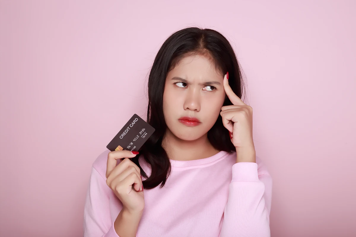 Woman pondering with credit card in hand