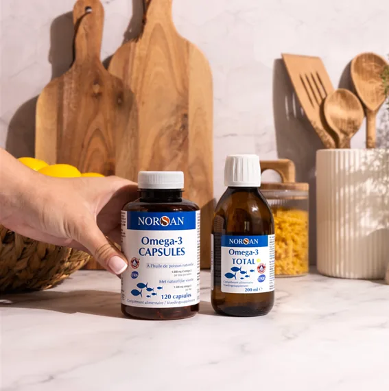 Deux compléments NORSAN aux oméga-3 total, en huile et en capsules, dans une cuisine lumineuse et naturelle.