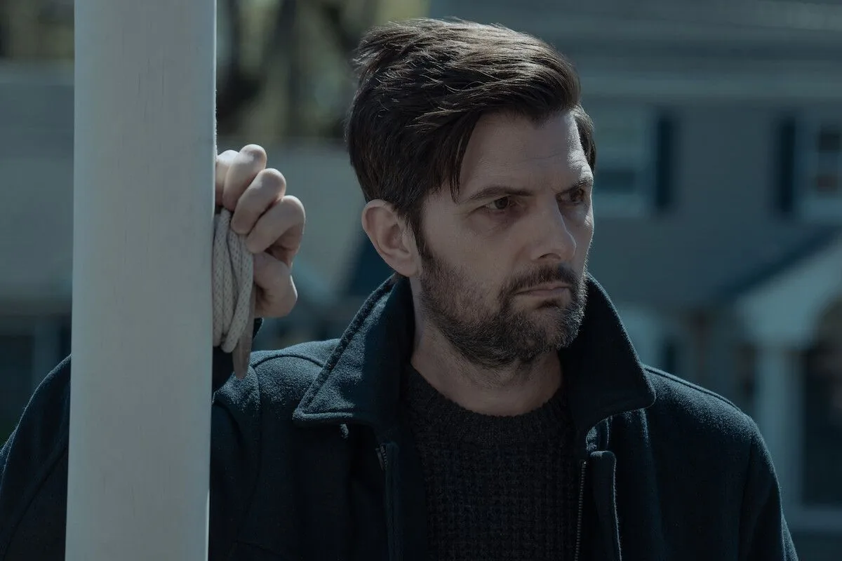 Adam Scott som Tom Kennedy i The Whisper Man står udenfor et hus med et alvorligt blik