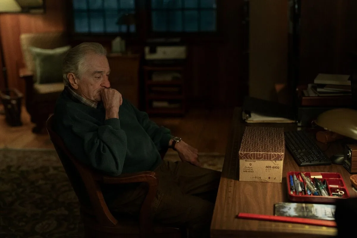 Robert De Niro sidder eftertænksom ved et skrivebord som Pete Willis i The Whisper Man