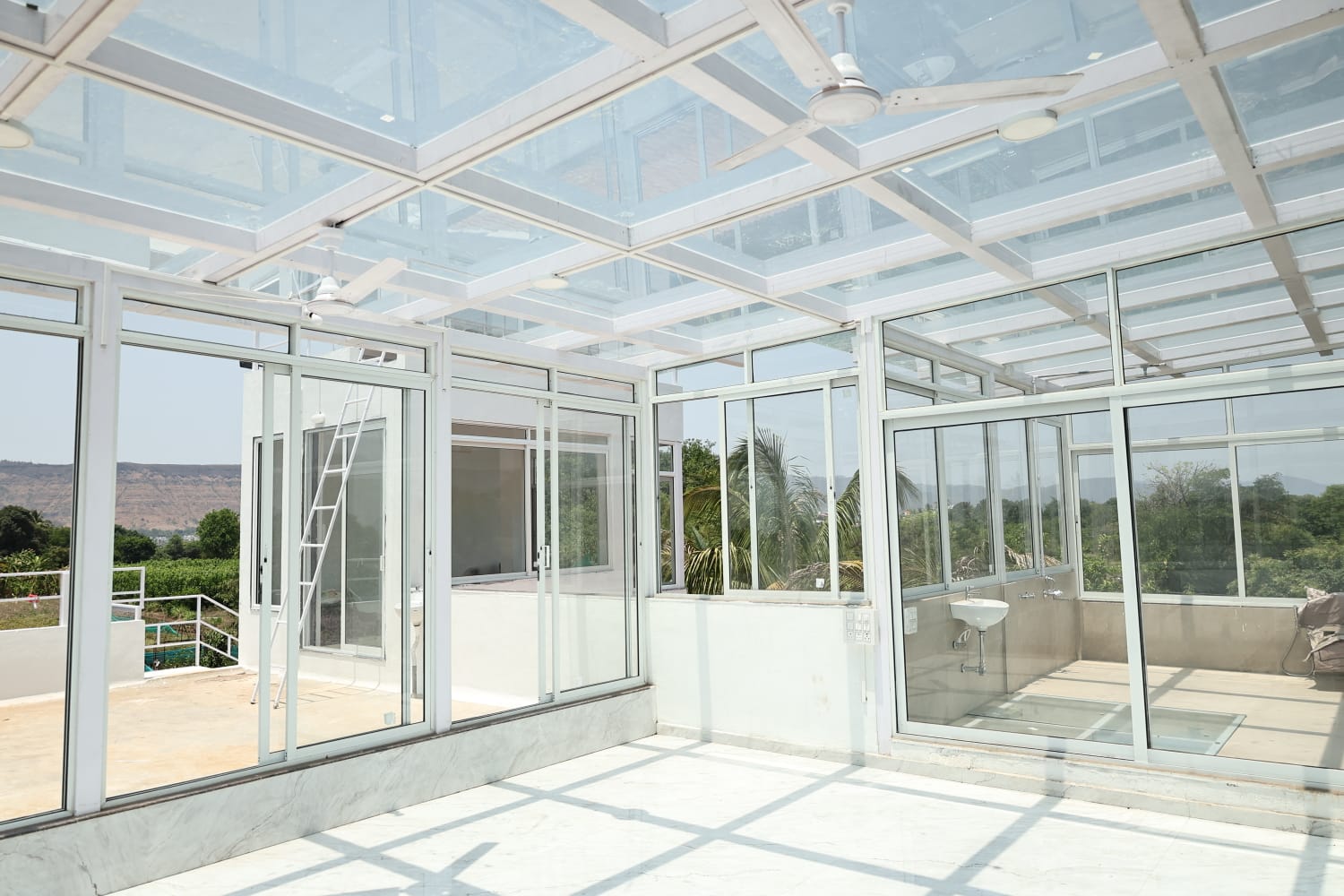 Contemporary sunroom at Aramzone Villa featuring glass walls and ceiling