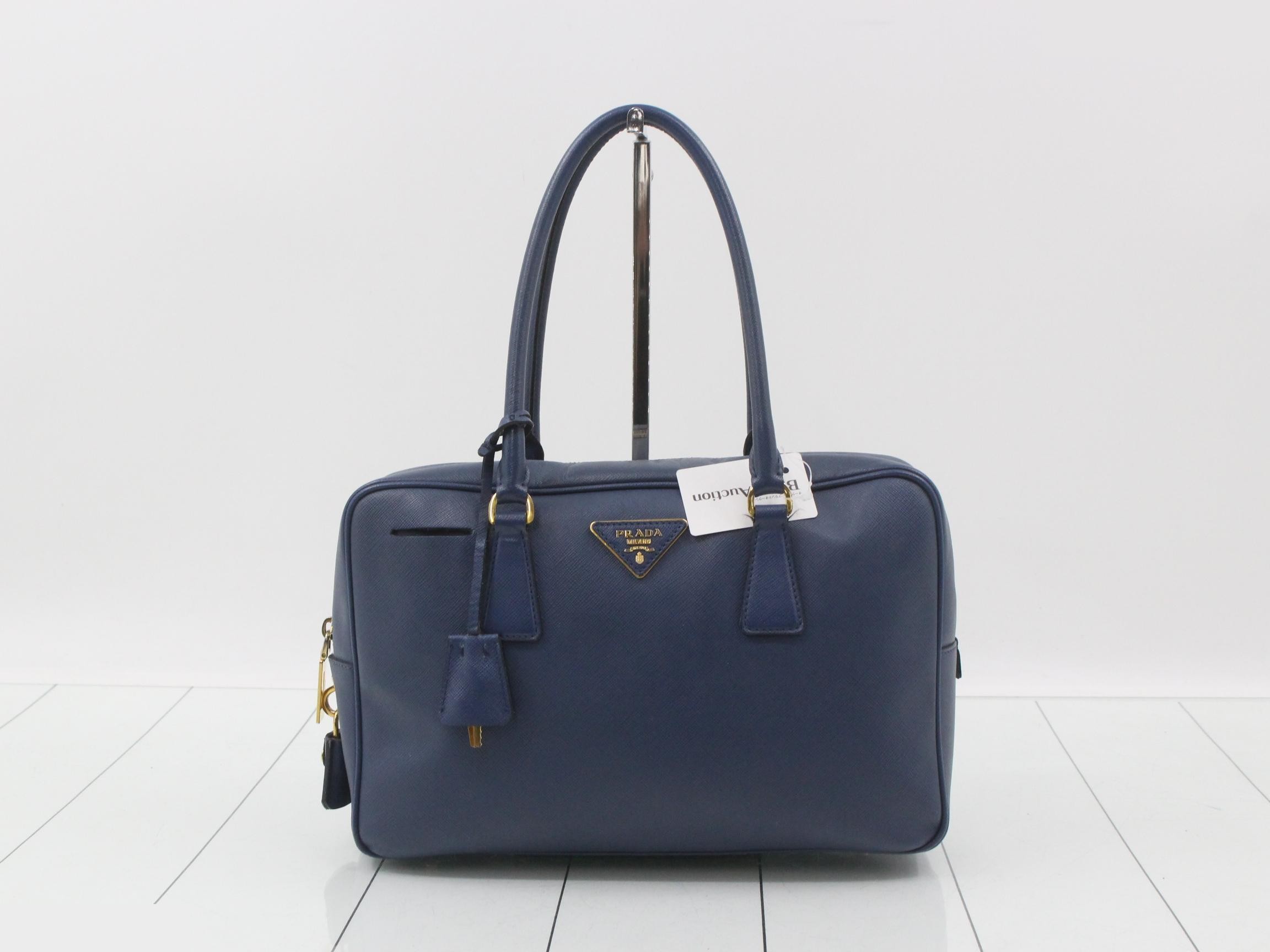 Saffiano leather handbag with triangular plate, blue tones.