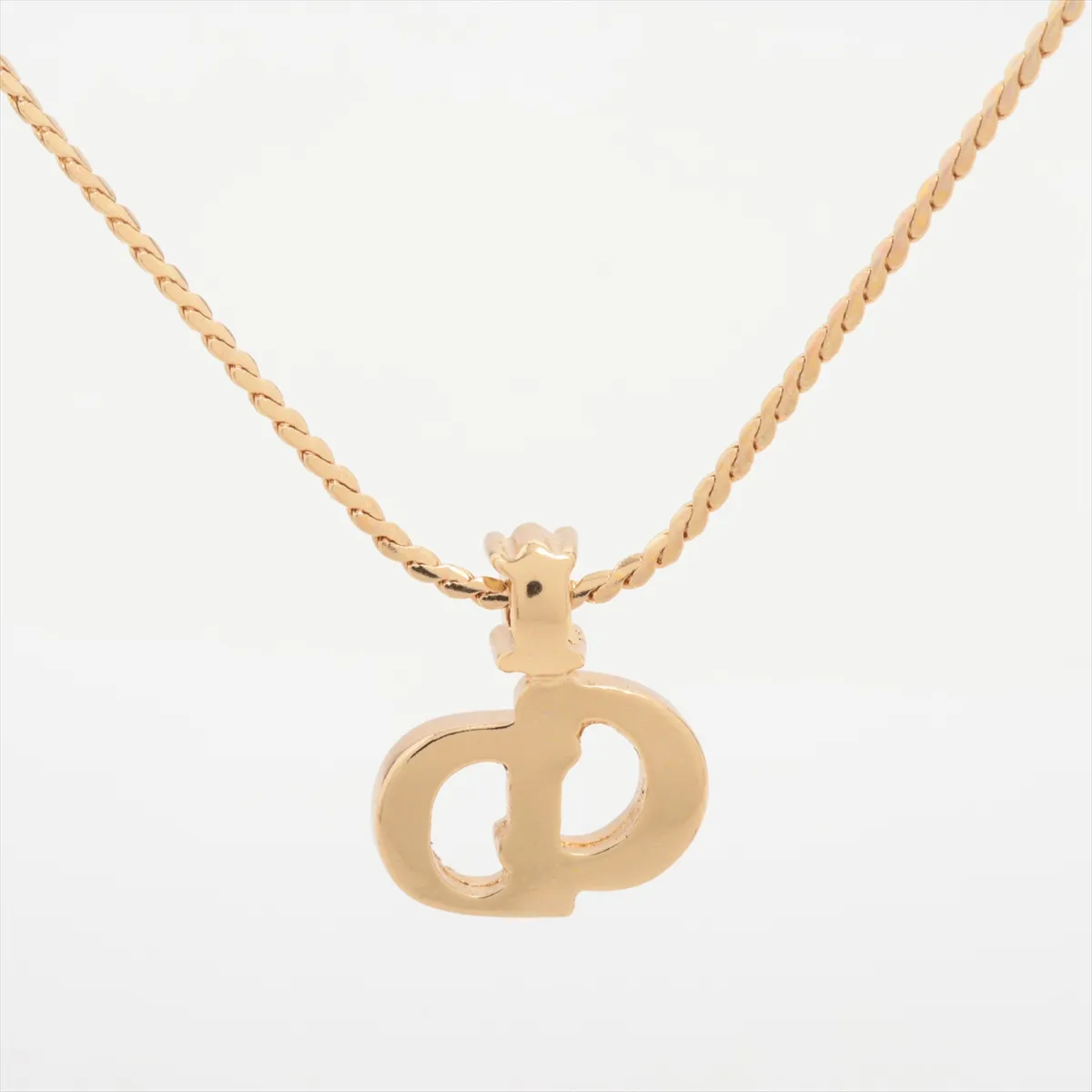 CD logo necklace, gold-plated with rhinestones. Shows wear, tarnishing, and discoloration. — view 2