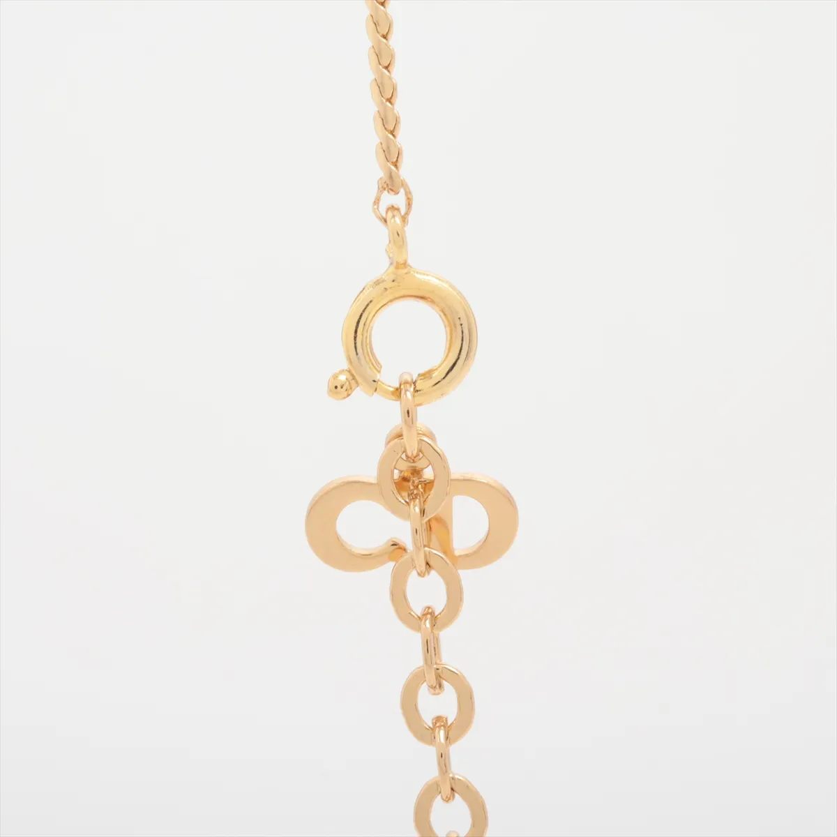 CD logo necklace, gold-plated with rhinestones. Shows wear, tarnishing, and discoloration. — view 3