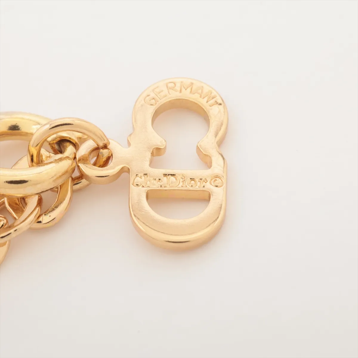 CD logo necklace, gold-plated with rhinestones. Shows wear, tarnishing, and discoloration. — view 4
