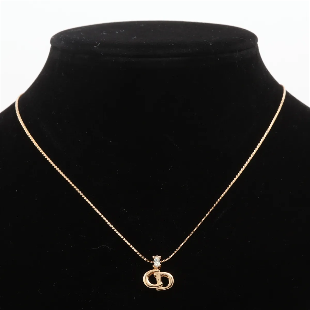 CD logo necklace, gold-plated with rhinestones. Shows wear, tarnishing, and discoloration. — view 5