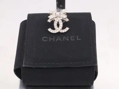 Metal and rhinestone earrings with a Coco Mark ribbon design, silver.