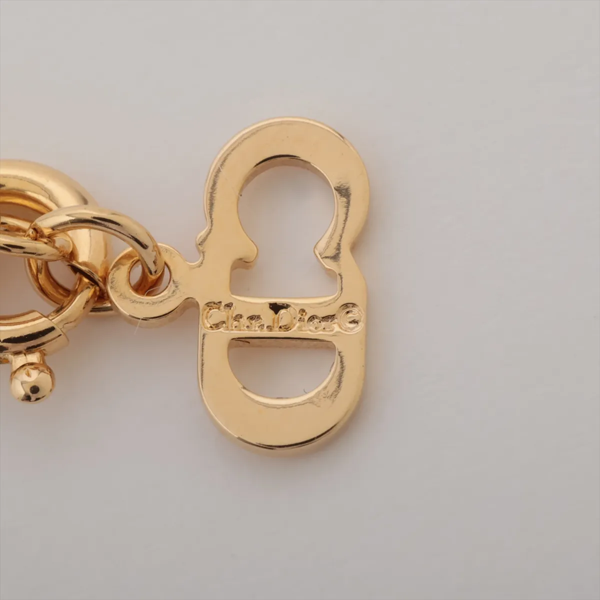 CD logo necklace, gold-plated with rhinestones. Shows wear, tarnishing, and stains. — view 4
