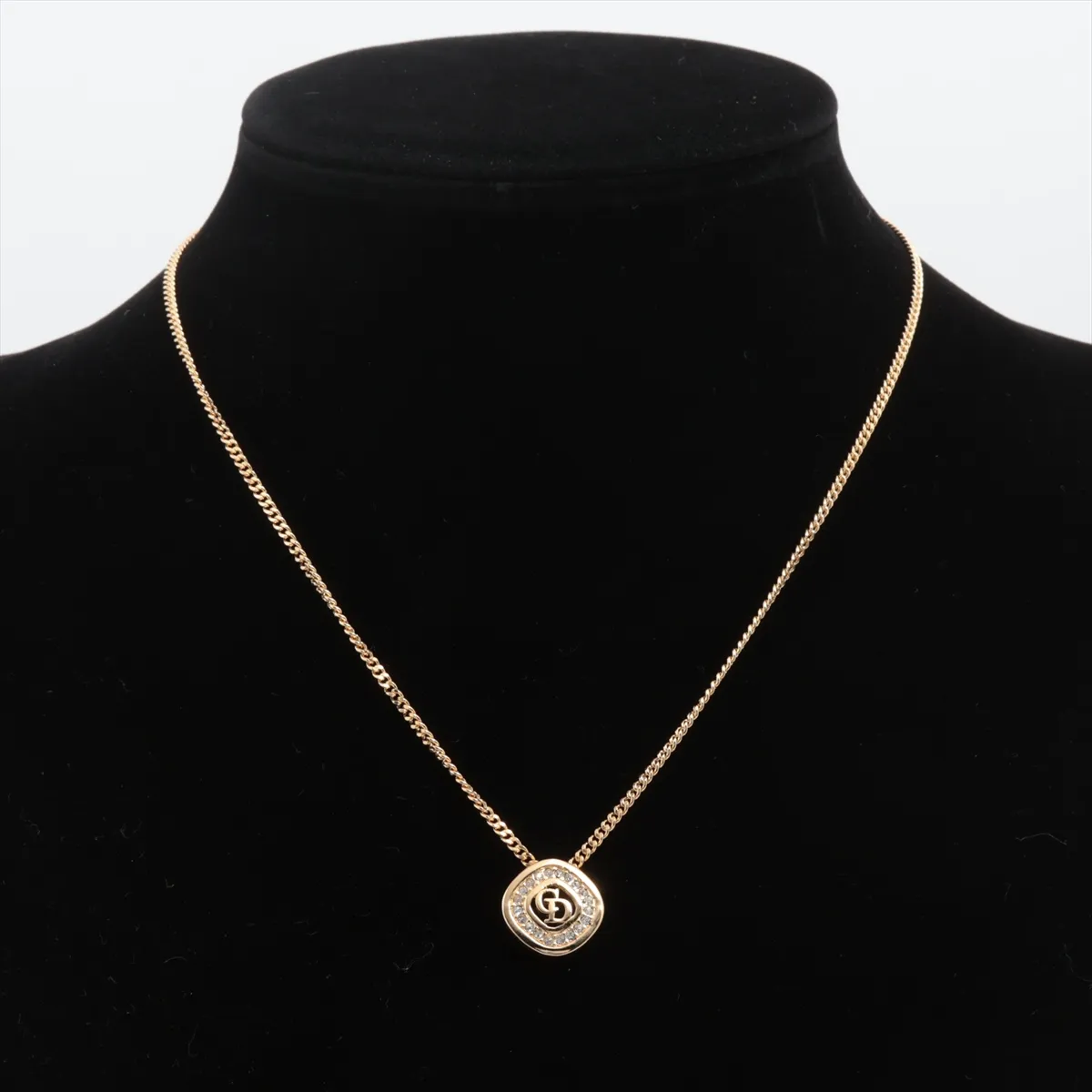 CD logo necklace, gold-plated with rhinestones. Shows wear, tarnishing, and stains. — view 5