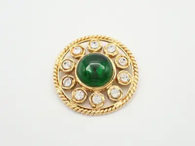 Green brooch with gold-plated stones and rhinestones.