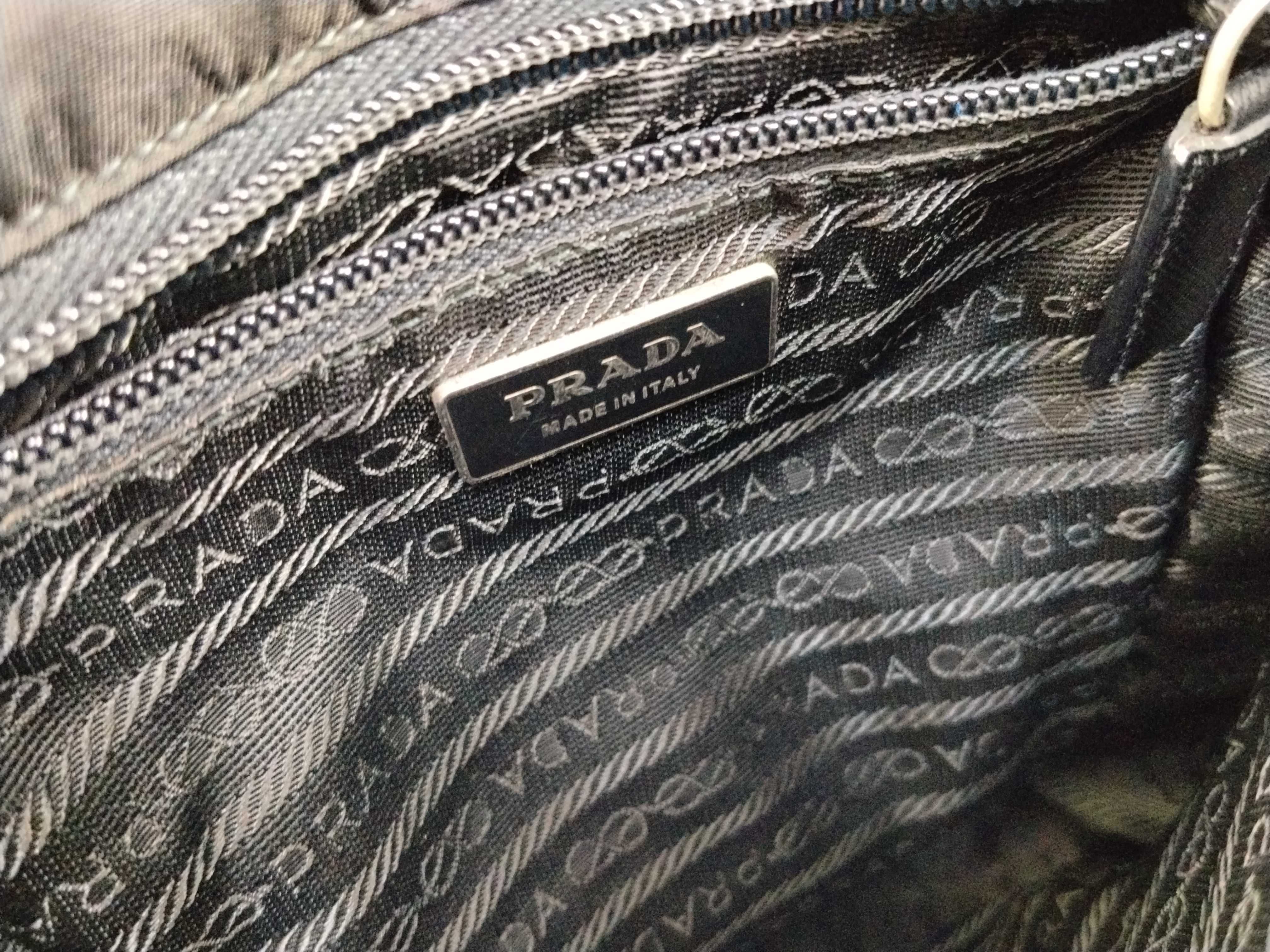 nylon shoulder bag with triangular logo plate, black nylon, white tag, and dust bag. — view 11