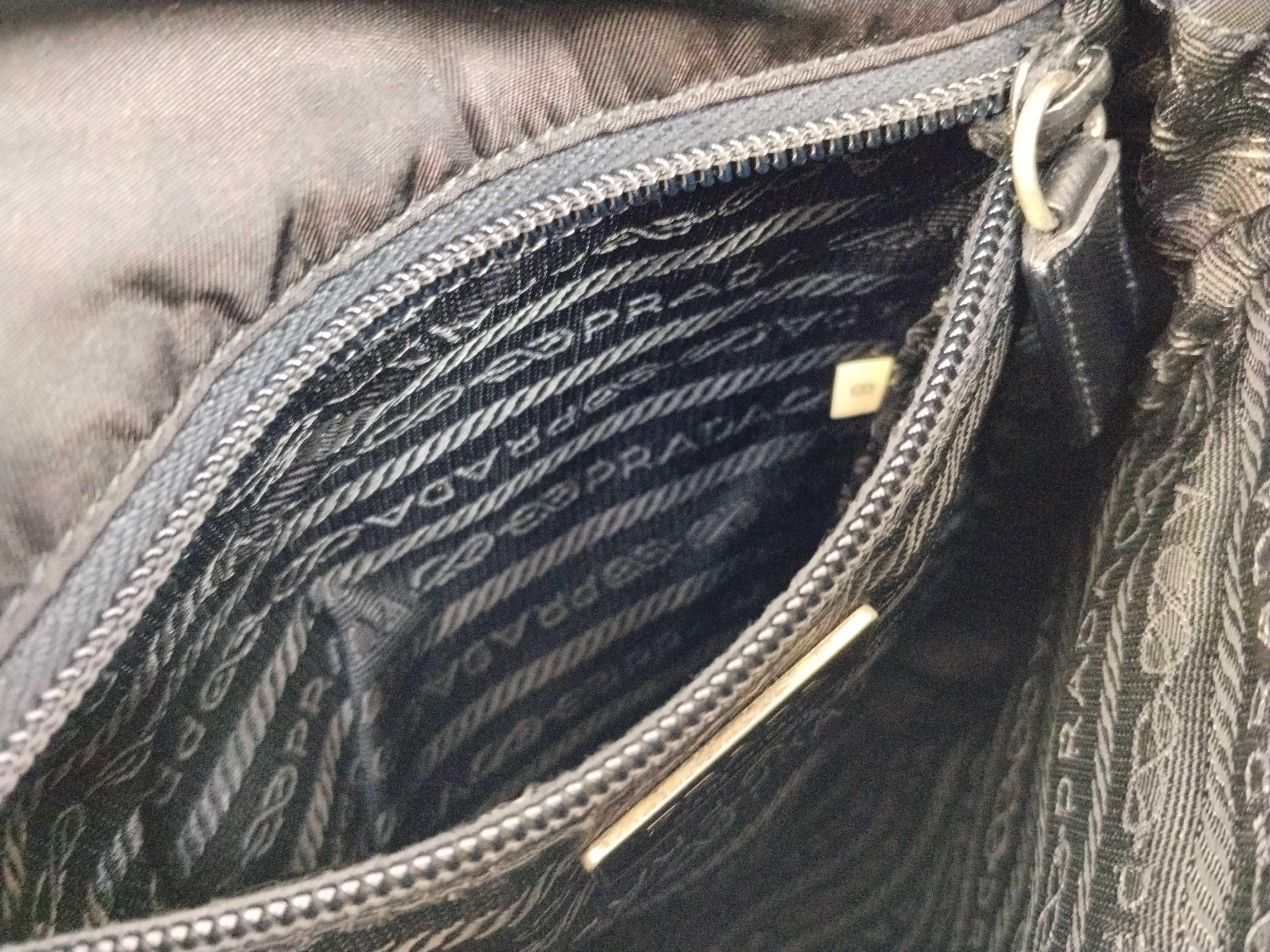 nylon shoulder bag with triangular logo plate, black nylon, white tag, and dust bag. — view 12