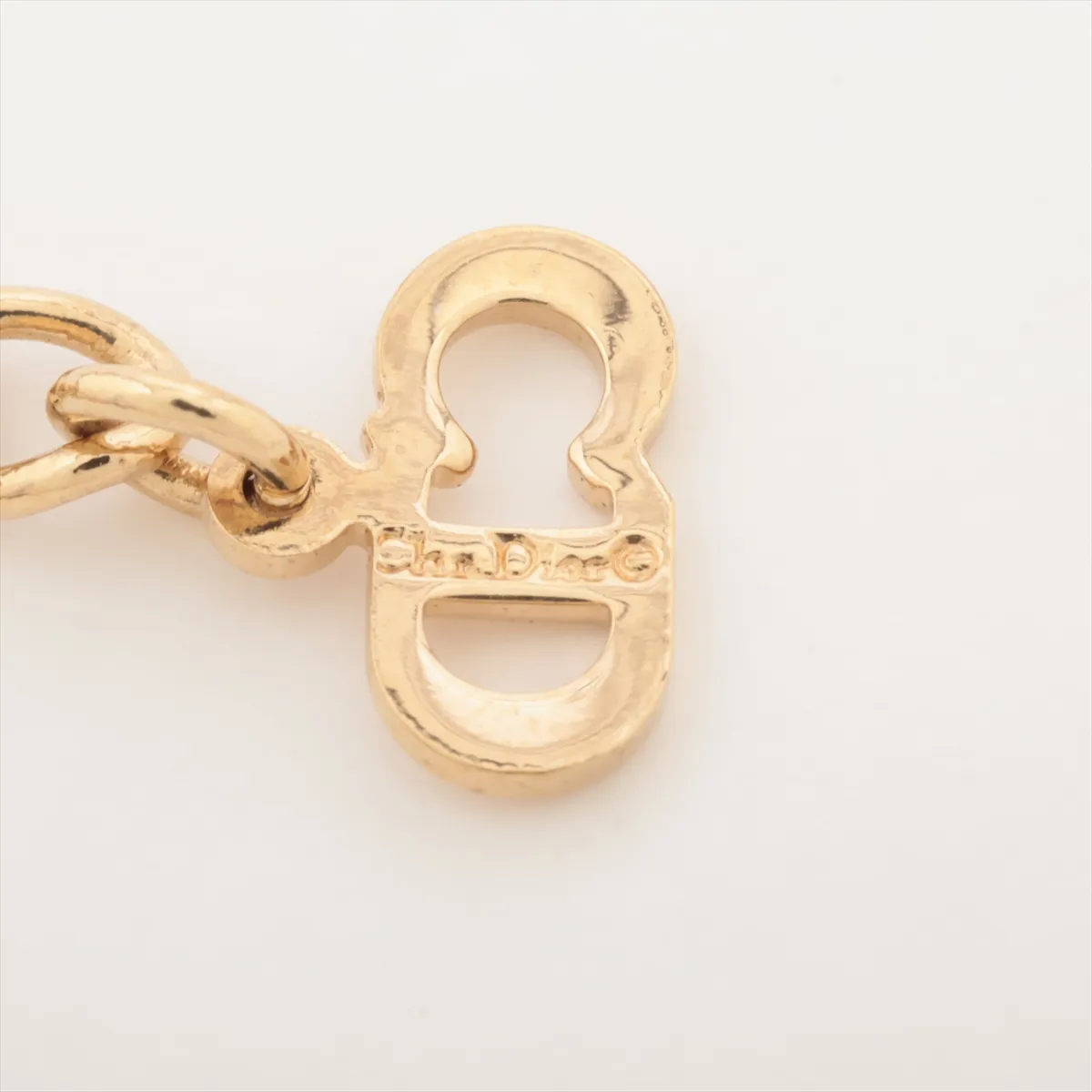 CD logo necklace, gold-plated with rhinestones. Shows wear, tarnishing, and discoloration. — view 4