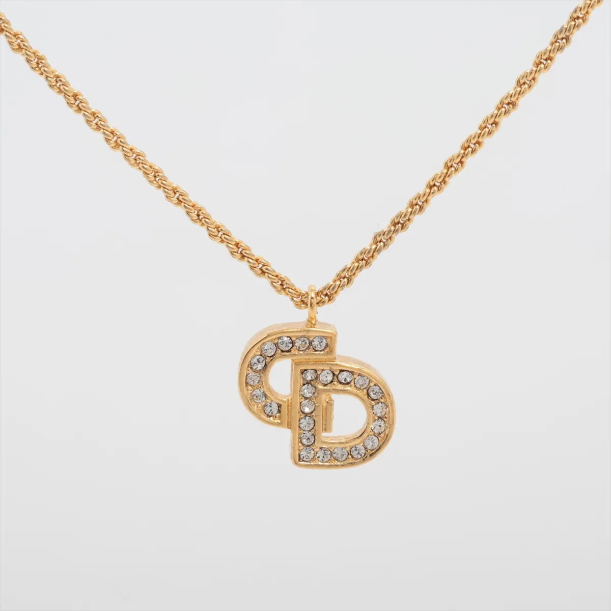 CD logo necklace, gold plated with rhinestones, shows signs of wear, tarnishing,