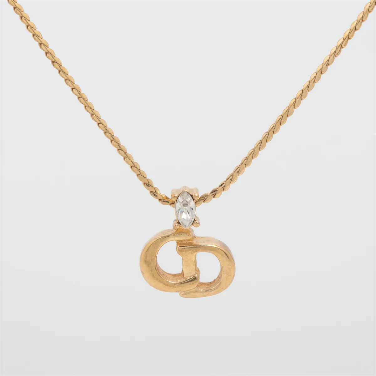 CD logo necklace, gold plated with rhinestones. Shows signs of wear, including